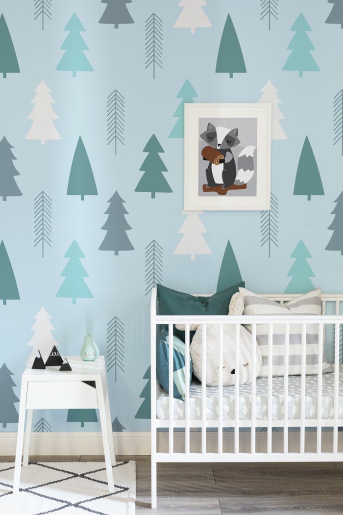 paredes pintadas, cama de bebé con cojines con caras, papel pintado de pinos, mesita blanca