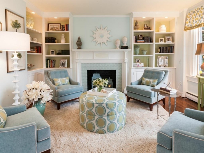 colores pastel, sala de estar con cuatro sillones en azul pastel, chimenea y estanterías, alfombra color crema