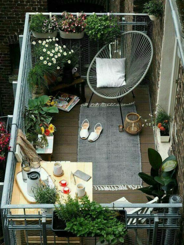 como decorar una terraza pequeña, balcón con tarima y silla Acapulco, mesa con vasos, revistas, plantas y flores