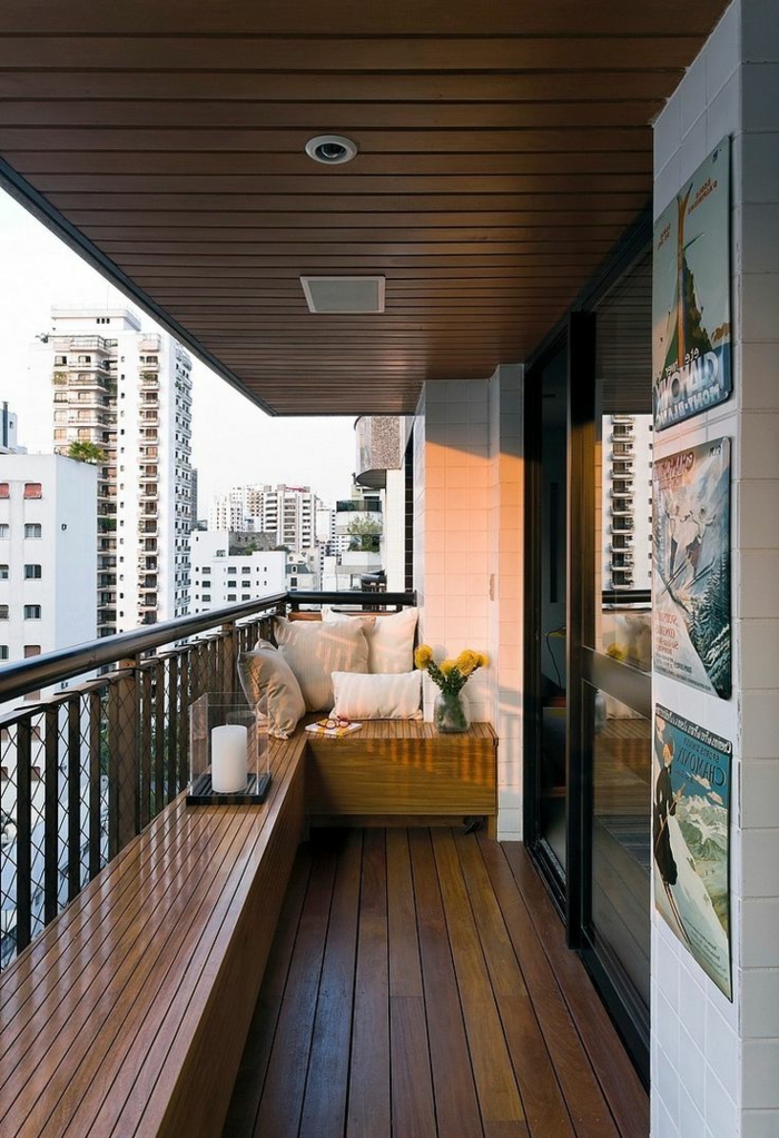 como decorar una terraza pequeña, balcón con suelo tarima, banca con candela, cojines y flor, paisahe urbano