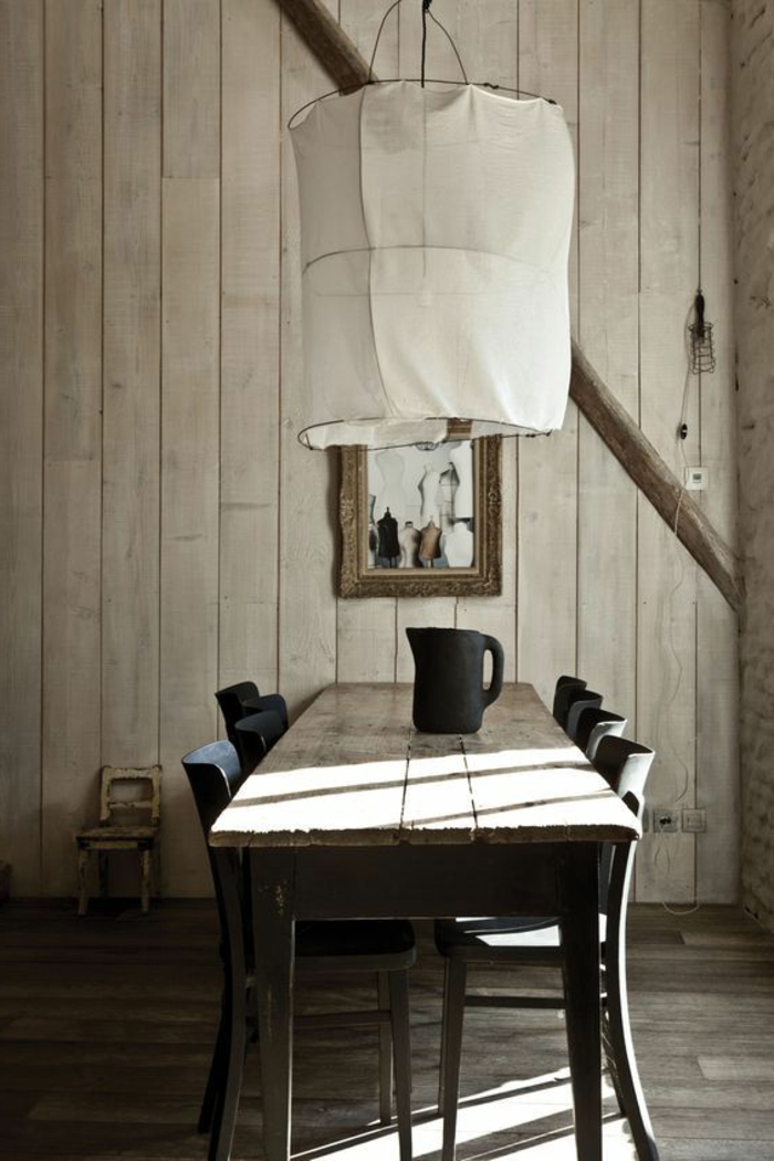 decoracion de comedores, comedor con mesa de madera rústica, sillas negras, pared de madera, lámpara blanca colgante, jarra
