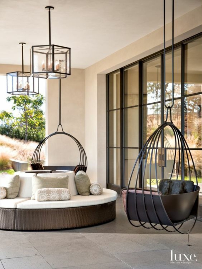 decoracion jardin, terraza con sillones colgantes y sofá redondo, suelo de baldosas, lámparas colgantes y ventanal