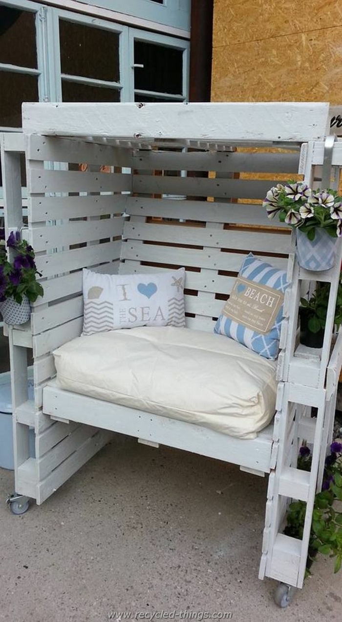 palets de madera, sillón cubierto de jardín de palets blancos, cojines y flores