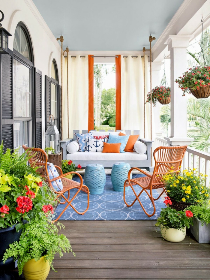 terrazas pequeñas, balcón con tarima, decoracion naranja y azul, sillas con cojines, macetas colgantes