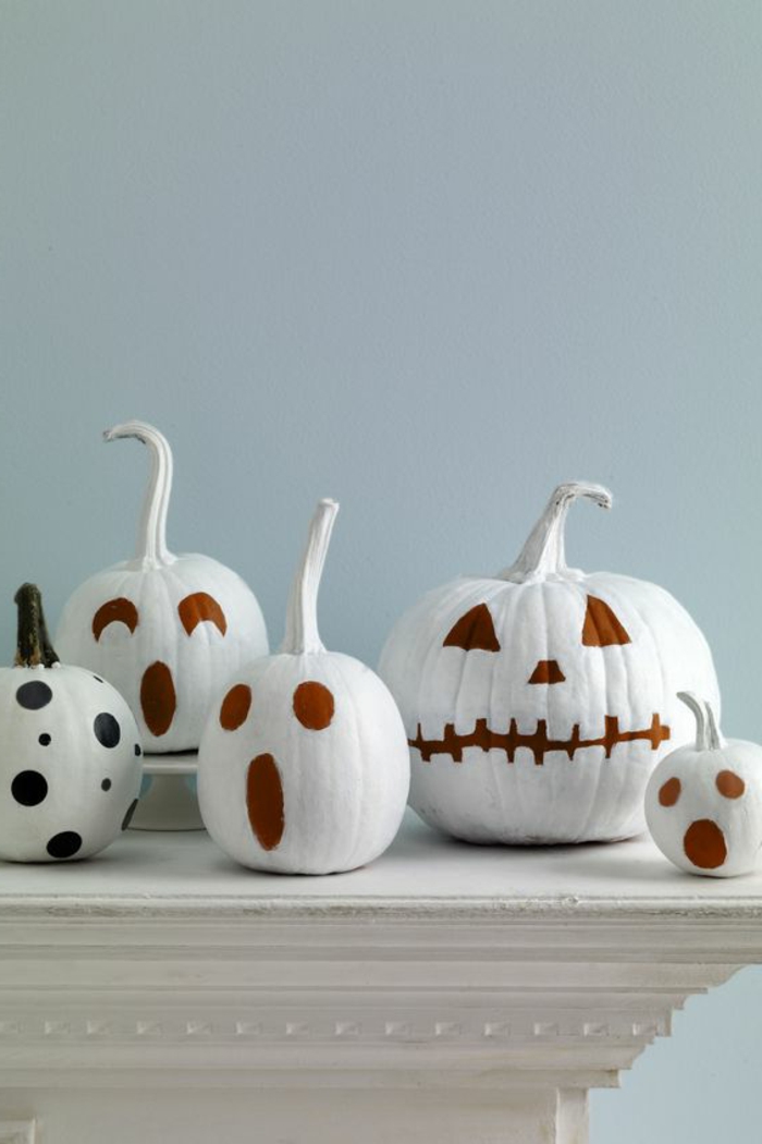 fotos de calabazas de Halloween, calabazas blancas con caras pintadas sobre mesa
