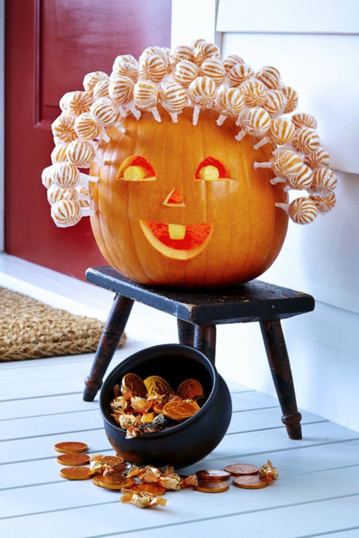 como hacer una calabaza de Halloween, calabaza tallada con cabeza de chupachups sobre silla
