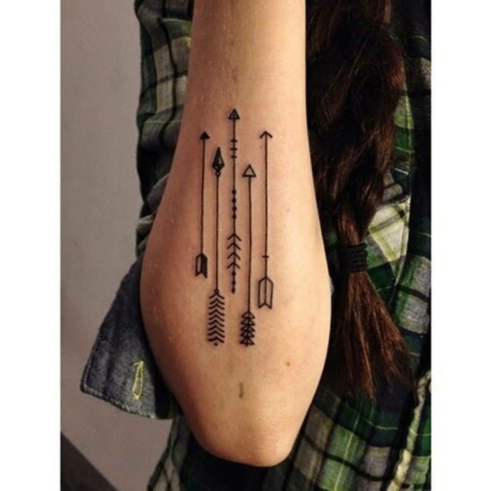 tatuajes en el brazo, mujer con trenza y tatuaje con flechas en el antebrazo