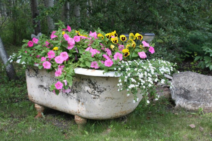 restaurar muebles, bañera de cerámica convertida en maceta de jardín con plantas con flor