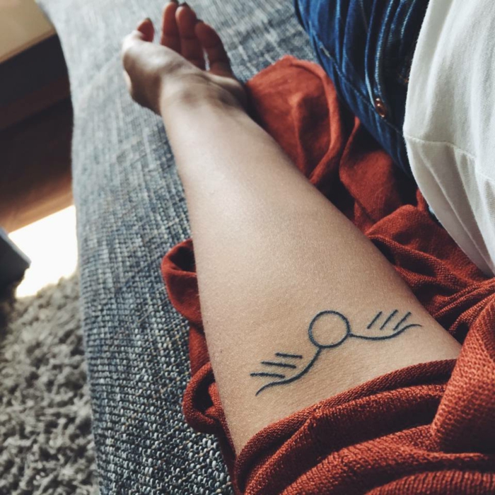diseños de tatuajes, mujer con tatuaje de sol estilizado acostada