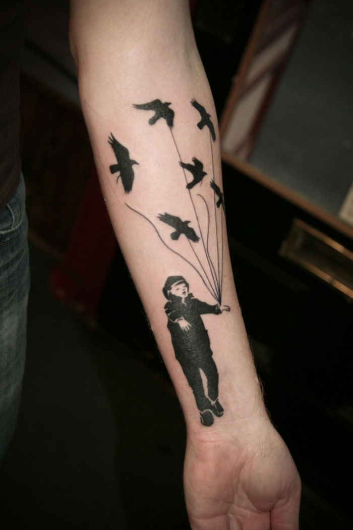 diseños de tatuajes, tatuaje en antebrazo con chico y pájaros en cuerda