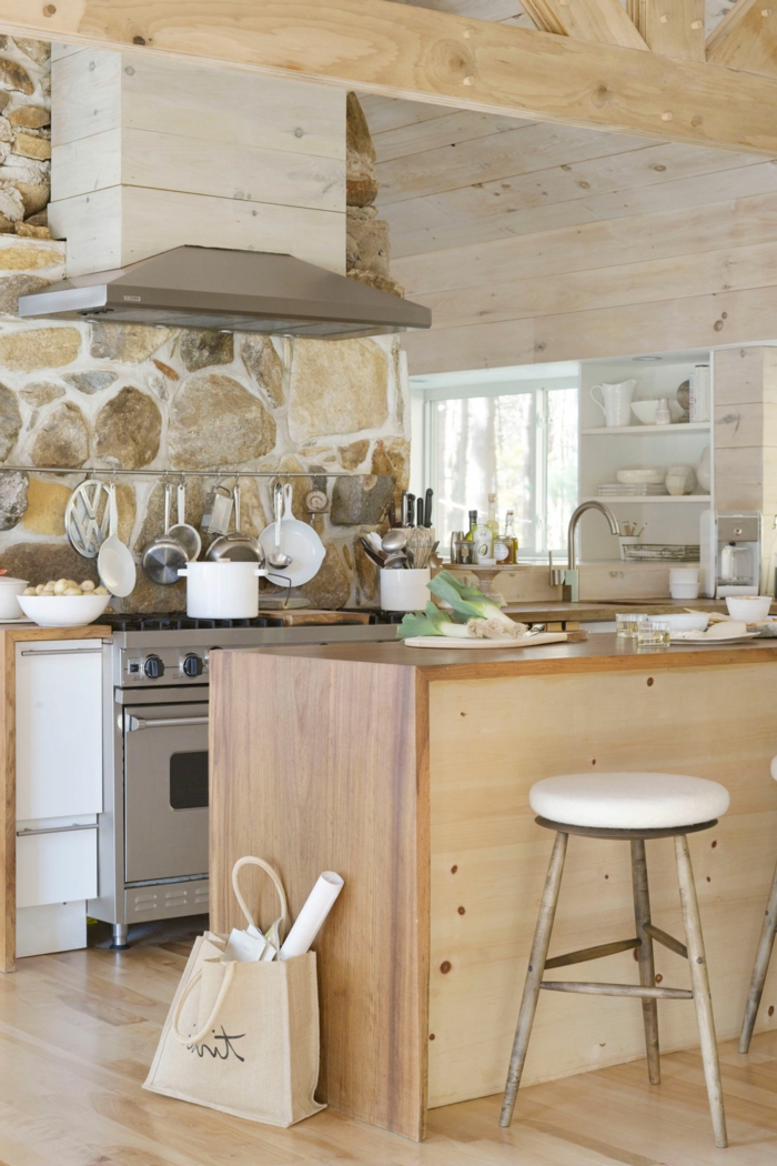 cocinas modernas pequeñas, cocina rústica con pared de piedra, madera clara, sartenes colgantes, campana extractora