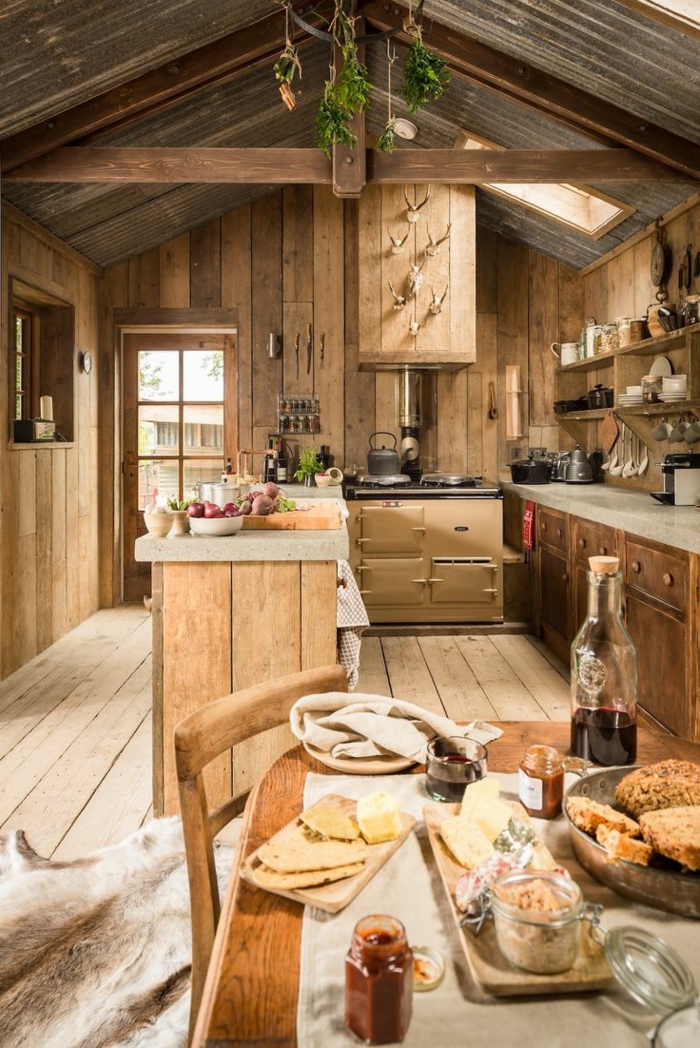 cocinas con encanto, cocina de madera rústica con isla, techo con vigas, mesa con quesos, decoración cabezas de ciervo