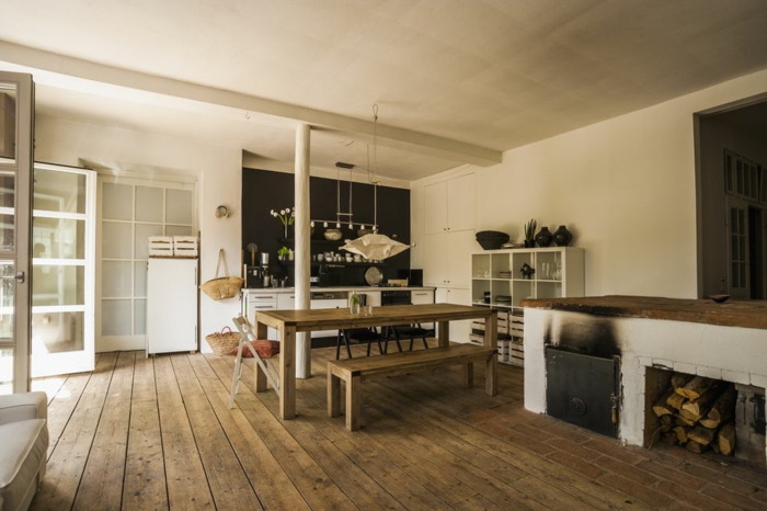 cocinas rusticas de obra, cocina con suelo de tarima, mesa de madera con bancos, paredes blancas, chimenea y leña