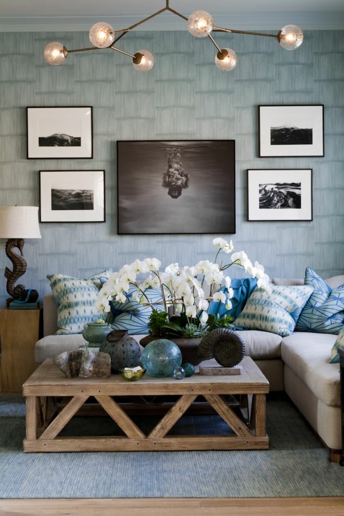 salones modernos, salon en azul, mesa de madera con flores blancos, cuadros, cojines y bombillas