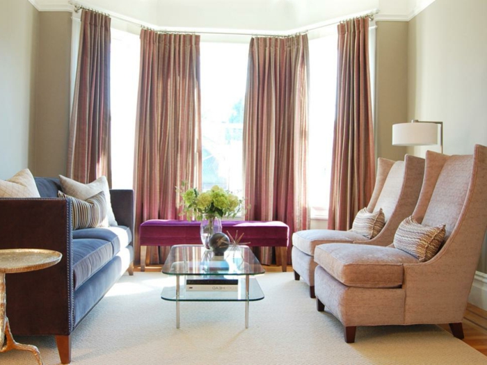 salones con encanto, salón con techo alto, grandes cortinas, sillones rosados, sofá azul, mesa de vidrio con flores