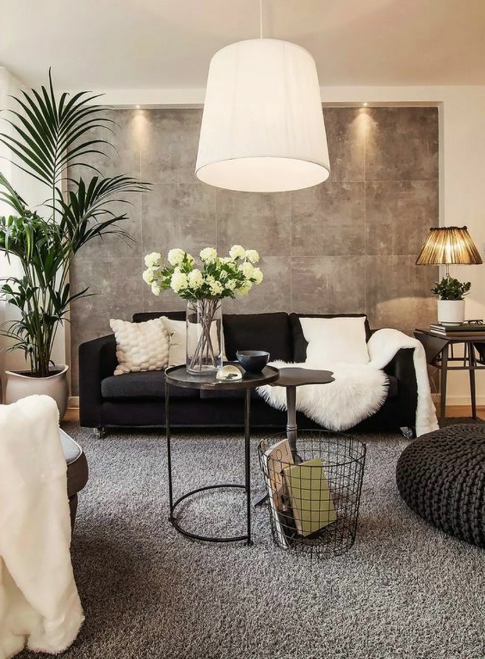 muebles de salon, salón pequeño con sofá negro con cojines blancas, palmera en maceta, jarra de cristal con flores, mesa redonda