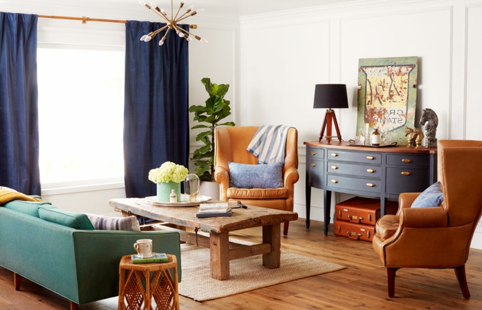 muebles de salon, salón pequeño vintage, sillones de piel, mesa de madera desgastada, sortinas azules, sofá verde y tapete