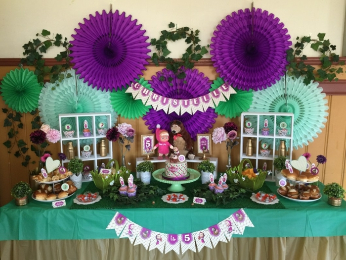 ideas para fiestas de cumpleaños, decoracion en verde y púrpura con guirnaldas y muñecas