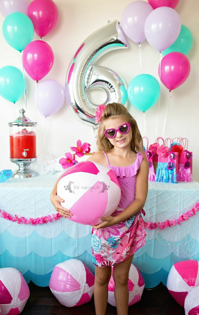 decoracion con globos, niña con gafas de sol rosa, globos azul y rosado, mesa con regalos