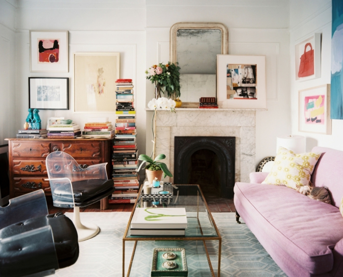 decoracion de salones, salón peque;o con chimenea y sofá lilá, sillas vintage negras, mesa rectangular de vidrio