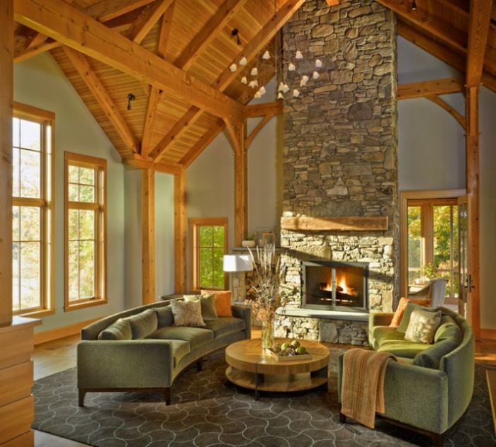 salones rusticos, salon con chimenea de piedra, techo de madera, mesa rotonda, sofás en verdepastel