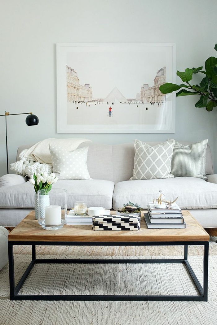 salon, sofá beige y mesa rectangular de madera con tulipanes, cuadro con Louvre y planta verde