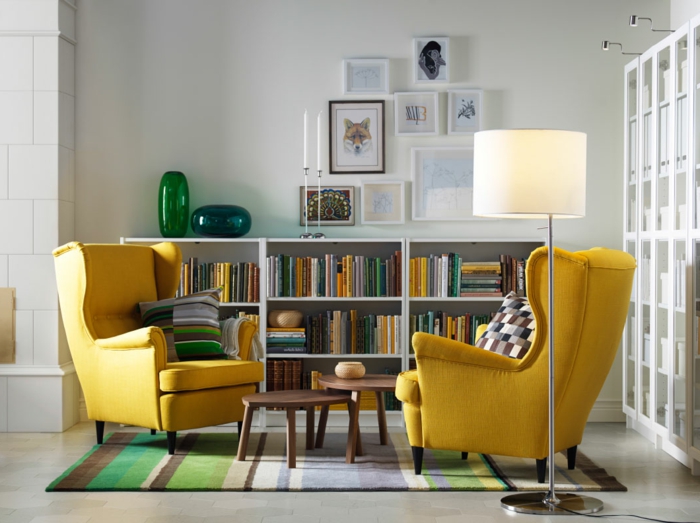 decoracion salones modernos, salón con dos sillones amarillos iguales, tapete rayado en verde y marrón y librería