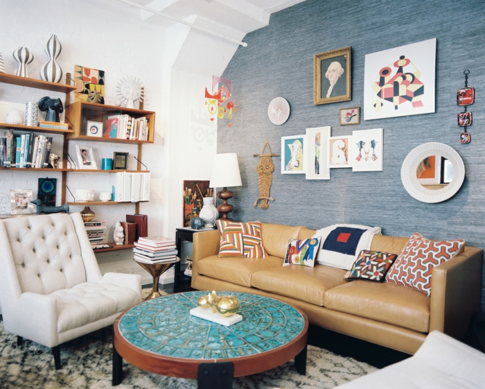 decoracion salones modernos, salón con pared azul, sofá de piel, mesa azul redonda, etsantería con libros