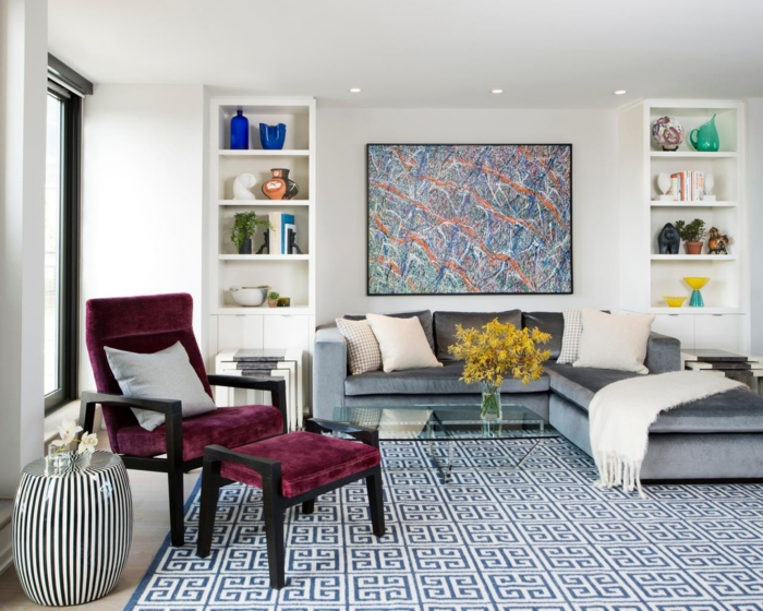decoracion salones modernos, salón con silla cama de terciopelo púrpura, sofá gris con cojines. estanterías blancas simétricas y cuadro