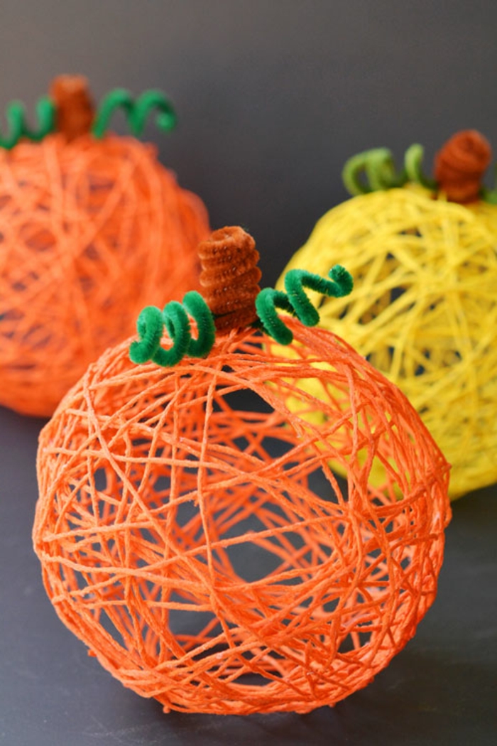 decoracion halloween, esferas modernas en anaranjado y amarillo hechas a mano, hilos enrollados alrededor de un balón