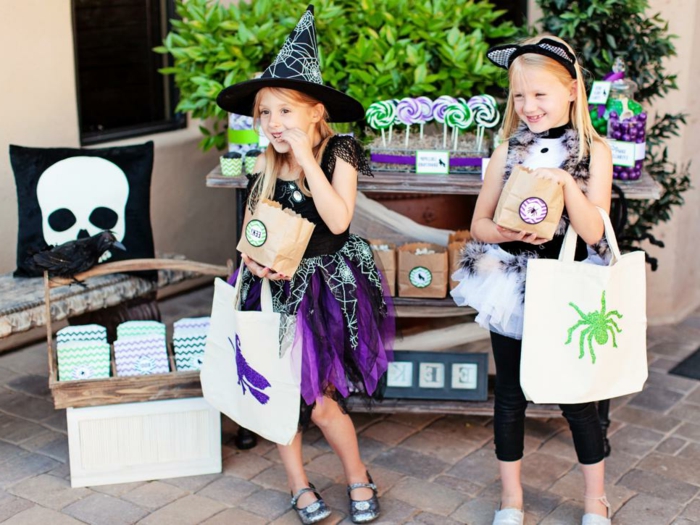 decoracion halloween, dos niñas con disfraces y accesorios con los motivos de halloween, chupa chups en espiralas coloridas