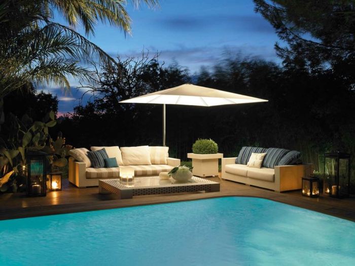diseño de jardines moderno, grande piscina y muebles en el patio, sombrilla con lámpara empotrada, sofás beige