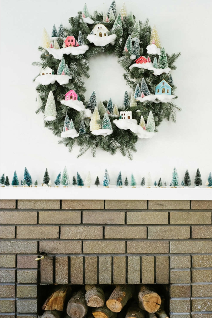 muerdago navidad, decoracion con chimenea y corona navideña verde con nieve y escarcha, casitas de color