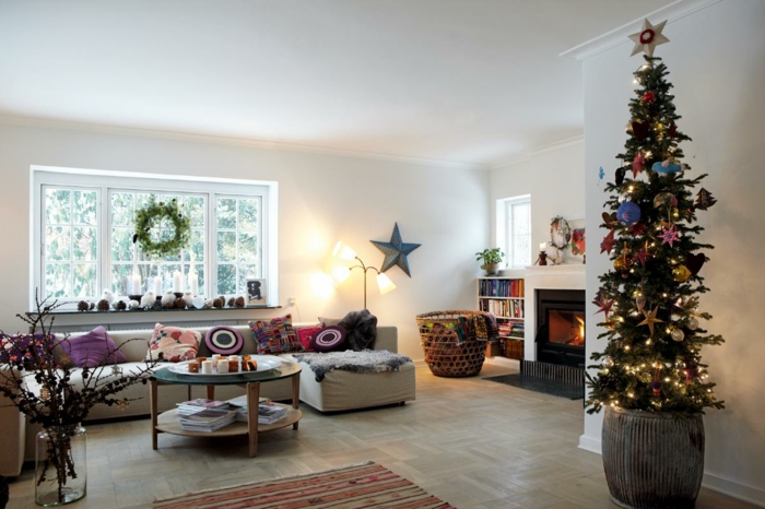 decorar árbol de navidad, árbol alto de poca anchura, salón grande decorado de cojines, grande ventana decorada con corona de navidad