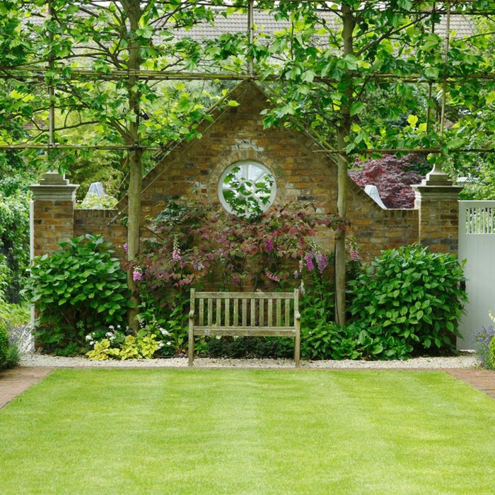 casa y jardin, propuesta para un jardín pequeño, cerca masiva de forma triangular y ventana oval, banco de madera