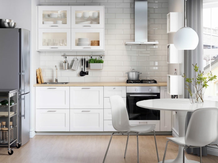 cocinas modernas blancas, cocina pequeña con comedor, mesa y sillas blancas de plástico, pared de ladrillo blanco