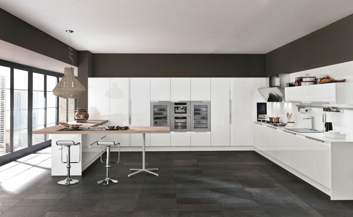 cocinas modernas, cocina grande con ventanalaes, muebles blancos laminados, suelo de baldosas negras, barra forma L d madera clara