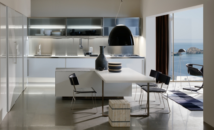 cocina blanca, cocina moderna con mesa en forma L, muebles altos con puertas transparentes, ventanal con vista al mar, sillas y lámpara negras
