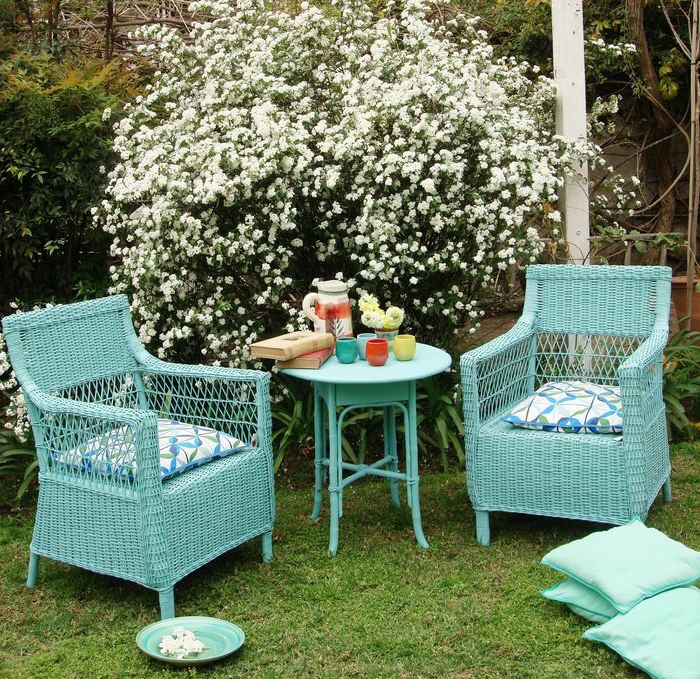 decoracion de jardines, muebles en color azul marino de madera, sillas de mimbre y mesa redonda, arbusto con pequeñas flores blancas