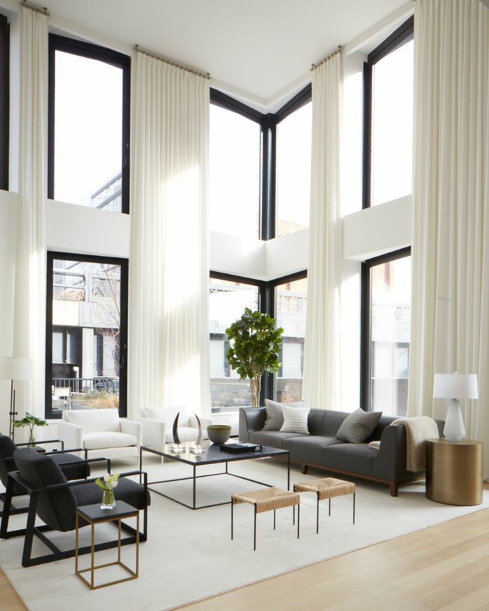 cortinas juveniles, ultra elegantes, en blanco, tela muy larga y aireada, sofá grande funcional en color gris, ventanales altos