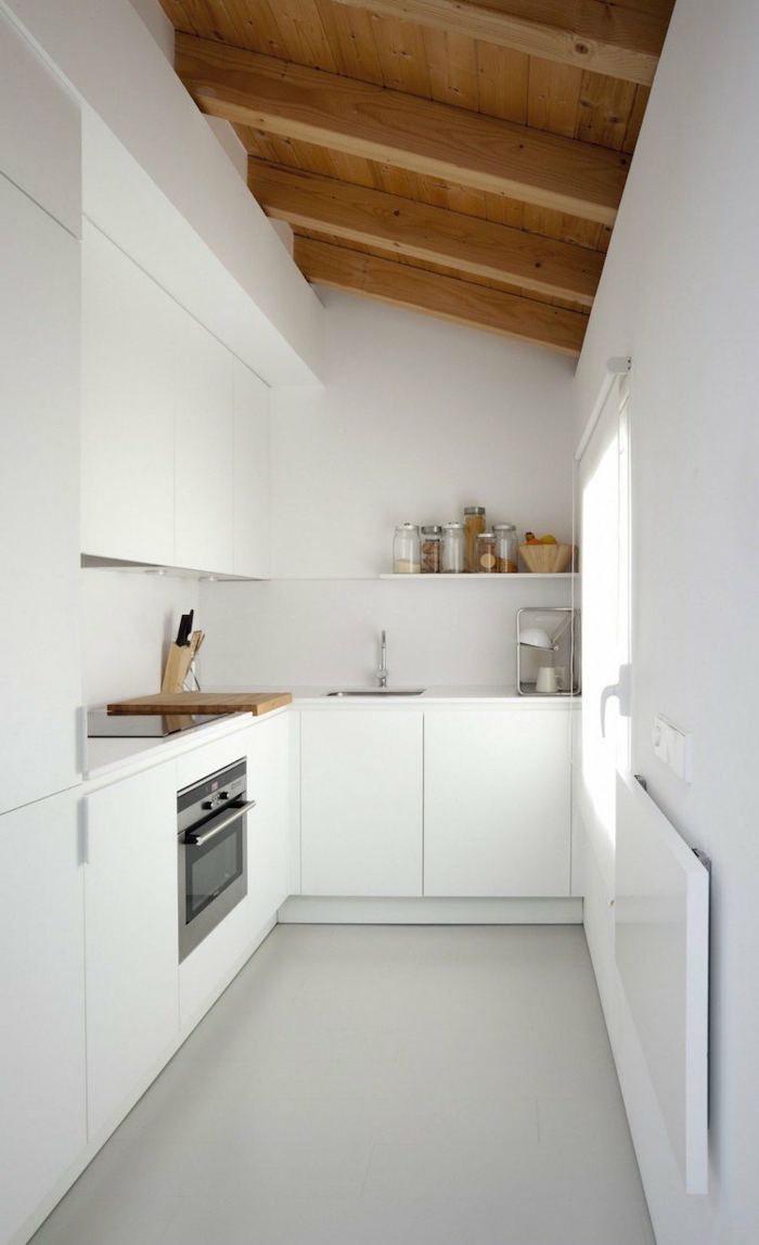 decoracion cocinas, cocina pequeña larga en blanco, techo inclinado con vigas de madera, ventana pequeña