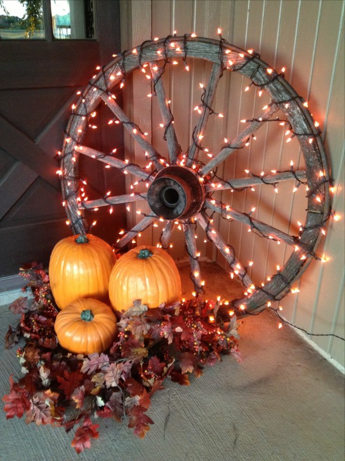 manualidades halloween, rueda de carroza con lámparas decorativas, tres calabazas y hojas de otoño en rojo