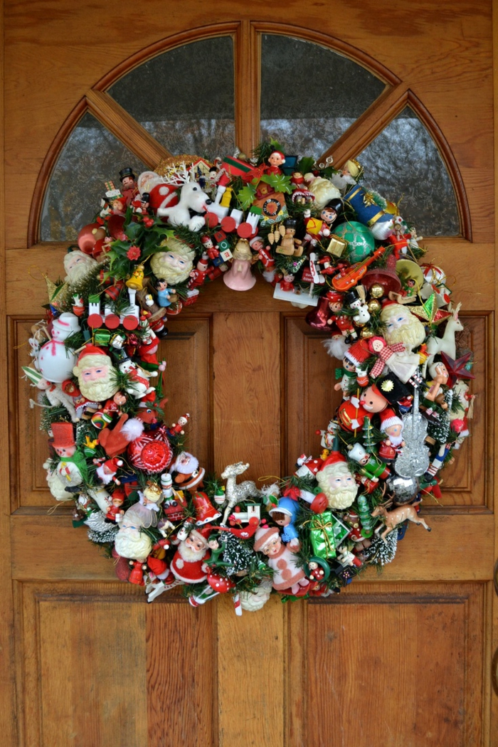 guirnaldas de navidad, corona de navidad en puerta de madera, base verde con muchos adornos, papa noel, enanos, juguetes