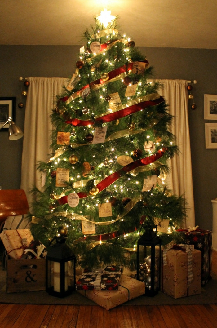 arbol navidad tradicional con adornos en rojo y dorado y grandes cintas envueltas al árbol como guirnaldas