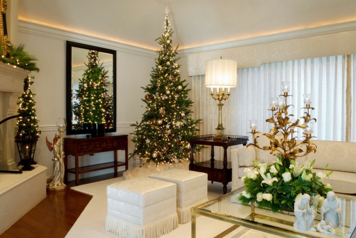 arbol navidad clásico para un salón grande de colores claros, adornos en dorado, pequeño árbol en la otra parte de la habitación