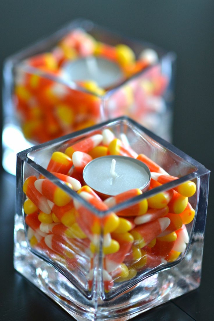 manualidades halloween, ceniceros pequeños de vidrio con caramelos en tres colores y pequeña vela redonda