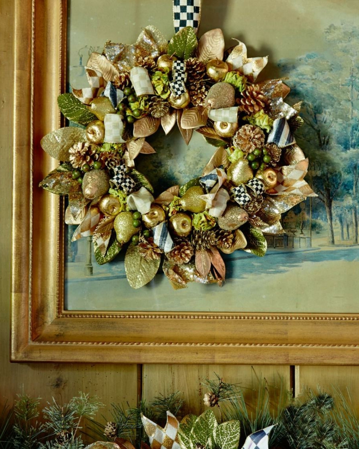 decoracion navideña casera, corona de navidad dorada con peras y manzanas artificiales, cuadro con marco de madera