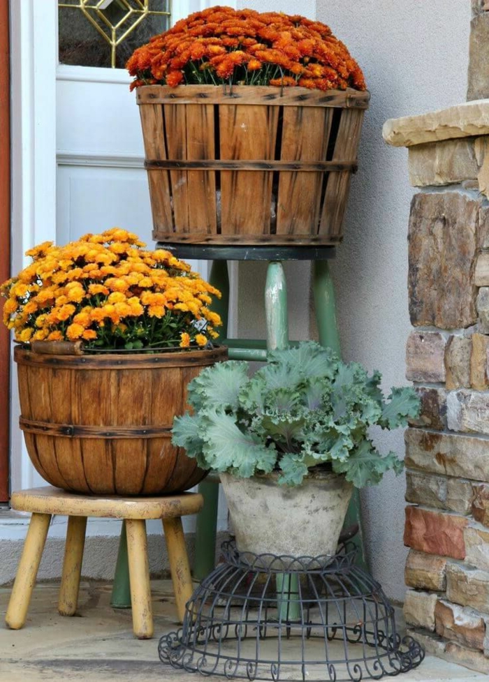 maceteros de madera, dos macetas de barriles de madera reciclados, crisantemos amarillos y anaranjados, maceta de cemento, puerta blanca