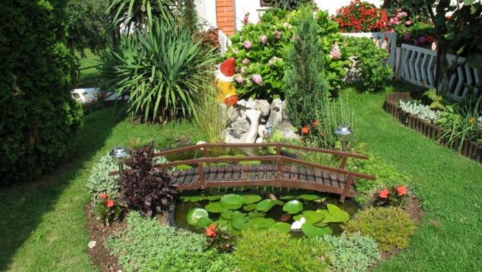 jardines con piedras, propuesta romántica para un patio pequeño, lago oval con lirios, fuente enano de madera