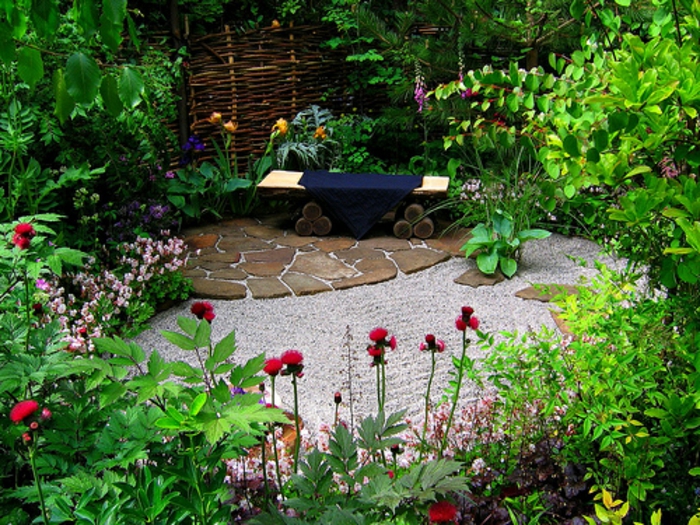 como hacer un jardín, rincón tranquilo rodeado de vegetación salvaje, pavimento de piedras, banco de diseño original de madera